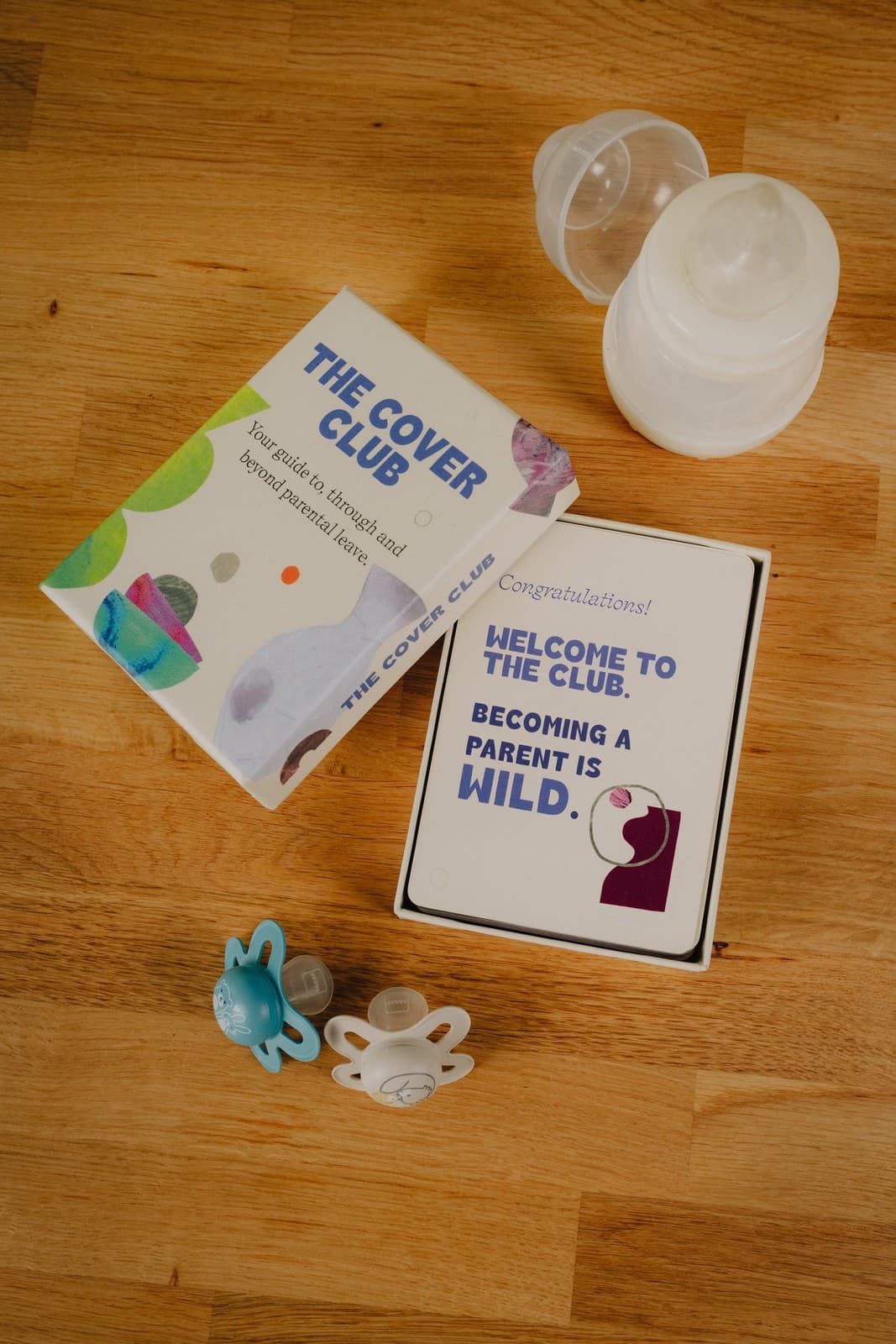 The Cover Kit box open, showing the welcome card alongside a baby bottle and pacifiers