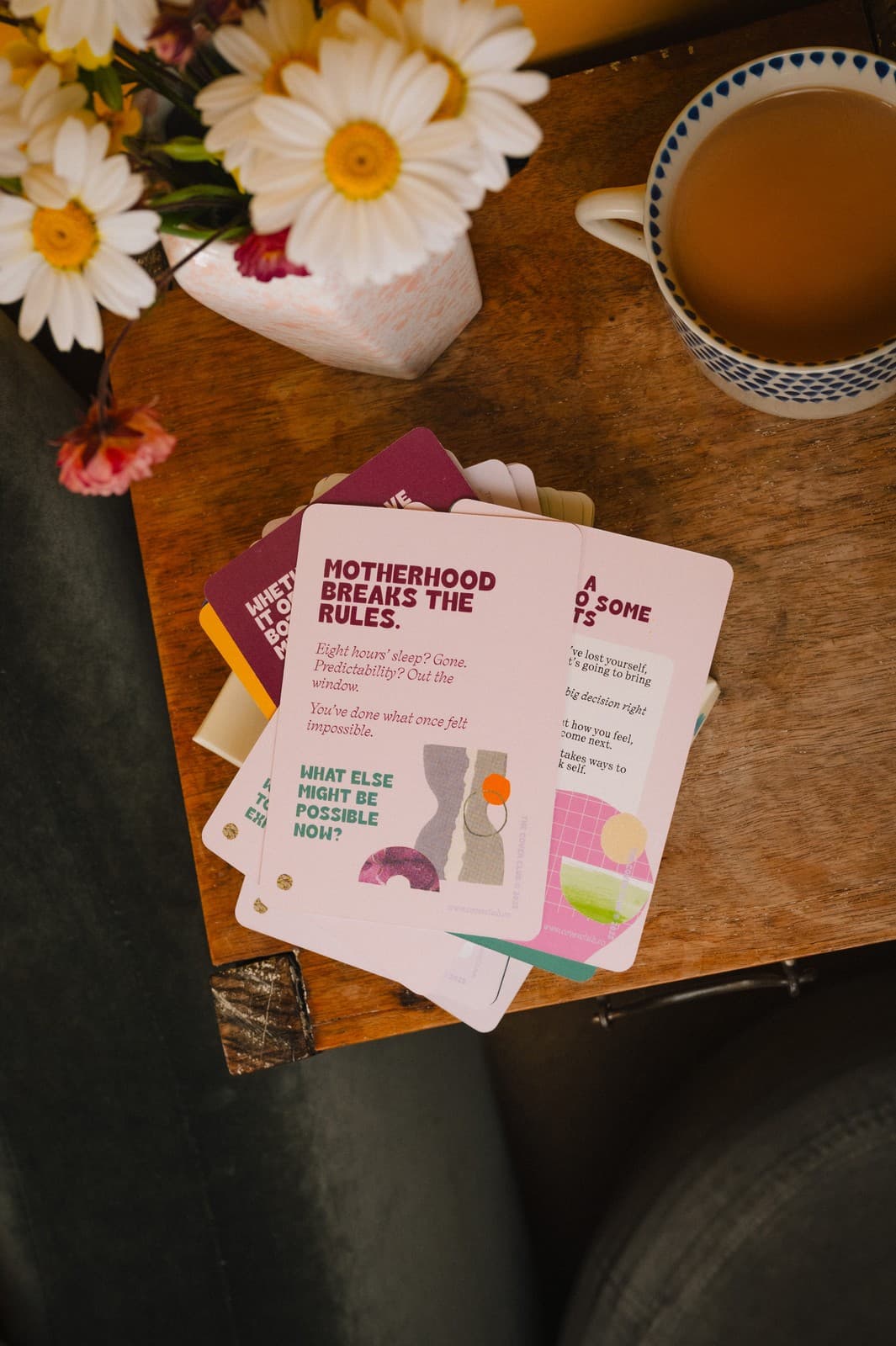 Cover Club cards fanned out on a table with daisies and a cup of tea